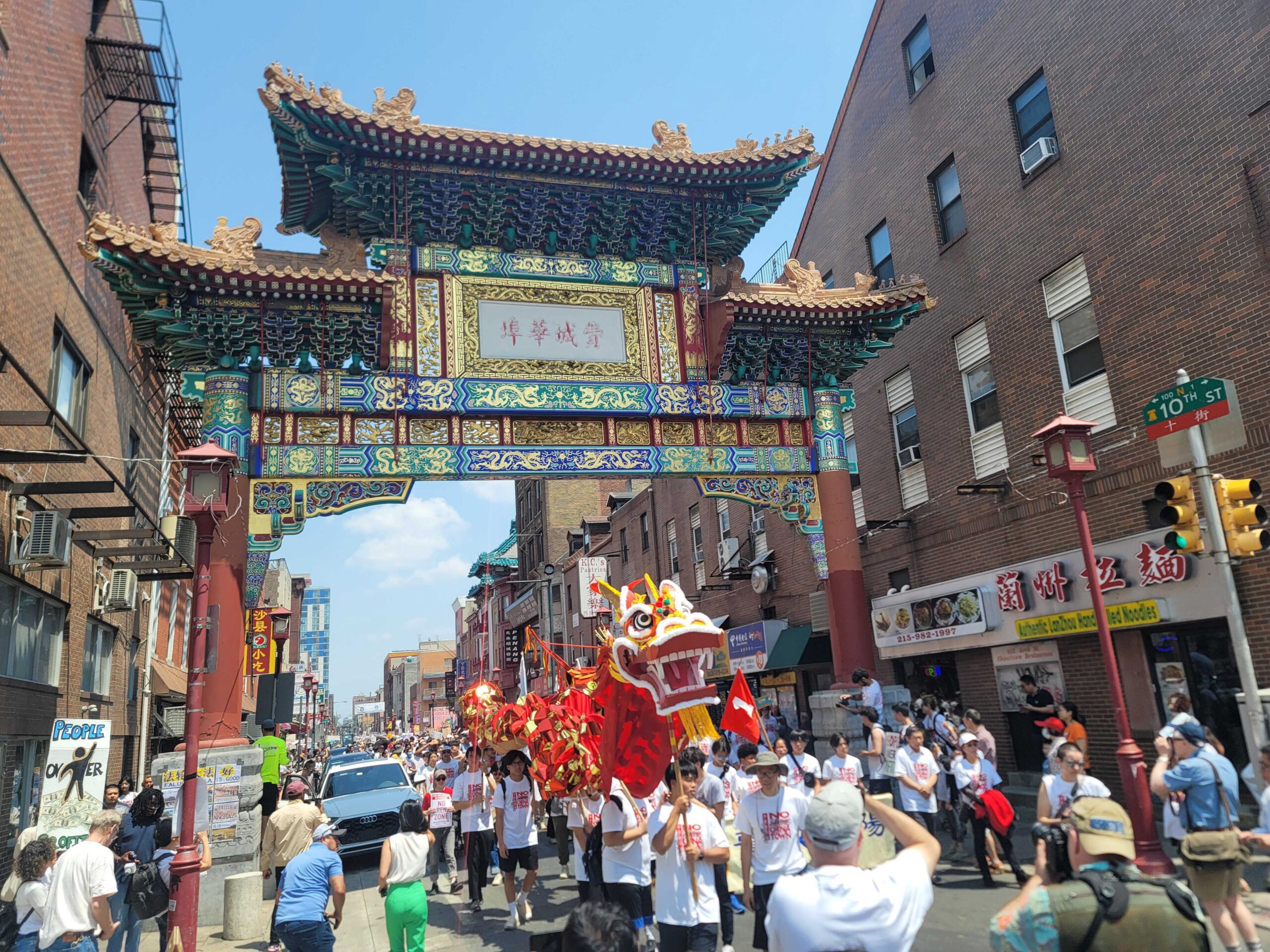 Several people marching, holding up a large dragon puppet, on 10th St in Chinatown, Philadelphia